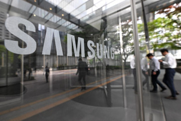 People walk past the Samsung logo displayed on a glass door at the company's Seocho building in Seoul on April 30, 2024.