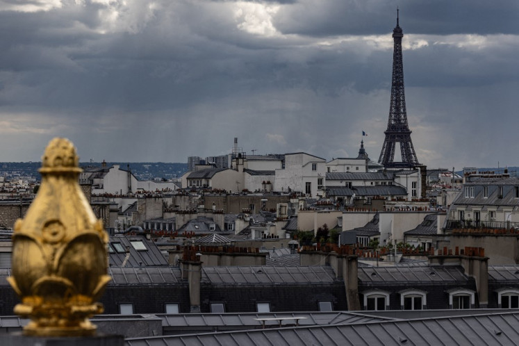 The Eiffel tower and roofs of Paris are pictured under a cloudy sky on May 23, 2024.