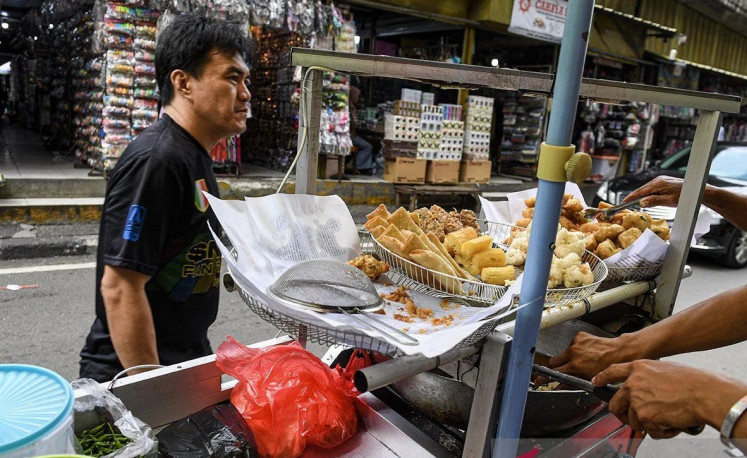 A customer buys fried snacks at Asemka Market in Central Jakarta on Feb. 28, 2024. 