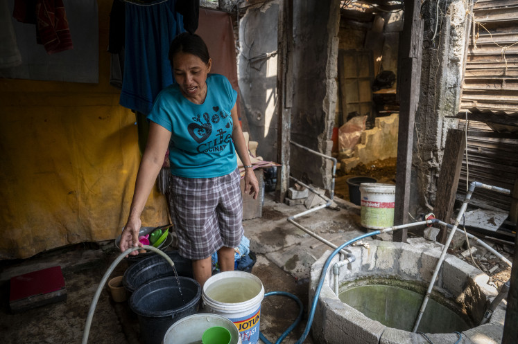 A former Kampung Bayam resident gets water from a well on May, 30, 2024, in their temporary shelter on Jl. Tongkol, Pademangan, North Jakarta. The Jakarta administration plans to build a new apartment complex to accommodate the residents that were evicted to make way for the construction of the Jakarta International Stadium (JIS) in 2020. 