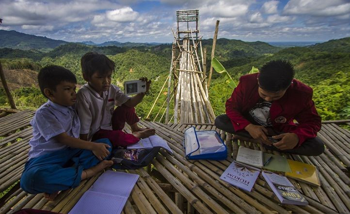 COVID lessons: Students learn online during the COVID-19 pandemic on Oct. 18, 2021 atop Merona Hill in Hinas Kanan village, Hulu Sungai Tengah regency, South Kalimantan. The students traveled 5 kilometers to reach the hill to access the internet, which was not available in their village.