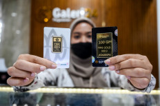 An official of state-owned pawnshop Pegadaian displays on May 20, 2024, a small gold bar minted by state-owned diversified miner PT Aneka Tambang (Antam) in Jakarta.