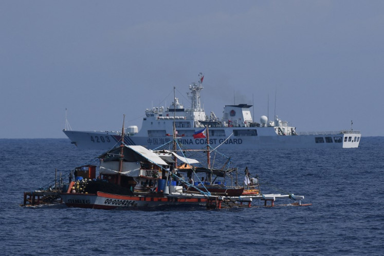 A China Coast Guard ship (right) sailing past a Philippine fishing boat with volunteers from the civilian-led mission Atin Ito (This Is Ours) Coalition on board, in the disputed South China Sea on May 16, 2024. A Philippine boat convoy bearing supplies for Filipino fishers said they were headed back to port May 16, ditching plans to sail to a Beijing-held reef off the Southeast Asian country after one of their boats was “constantly shadowed“ by a Chinese vessel.
