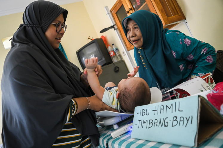A worker at the Merak integrated health post (posyandu) in South Tangerang, Banten, weighs a baby on May 17, 2024.