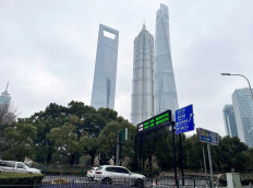 Cars travel past a display showing Shanghai and Shenzhen stock indexes near the Shanghai Tower and other skyscrapers at the Lujiazui financial district in Shanghai, China, on Feb. 5, 2024.