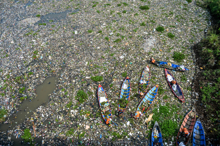 Workers use wooden boats on June 12, 2024 to collect plastic waste from the surface of the Citarum River in Batujajar, West Bandung regency, West Java. The mass of garbage floating on the river stretched 3 kilometers long and 60 meters wide and was estimated to weigh more than 100 tonnes, according to data from the West Bandung Environment and Forestry Agency as of June 7.