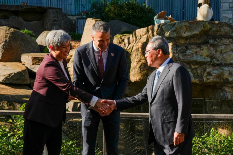Australia's Foreign Minister Penny Wong (left) shakes hands with China's Premier Li Qiang (right) as South Australian Premier Peter Malinauskas (center) looks on during Li's visit to the Adelaide Zoo in Adelaide, Australia, on June 16, 2024.