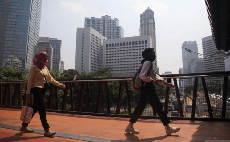 Personal protection: Wearing masks, pedestrians walk on a footbridge over Jl. Sudirman in Central Jakarta on Aug. 8, 2023. The city government had called on residents to protect themselves from air pollution with masks during outdoor activities.