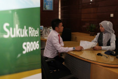 Customer Service (right) explains to customers (left) about the 2014 SR006 State Retail Sukuk at Bukopin Syariah Bank, Jakarta, Tuesday (18/02). The government offers SR-006 series Sukuk with a fixed fee of 8.75 percent per annum starting February 14 until February 28, 2014. The nominal value per unit is set at 1 million, with a minimum order of 5 million and a maximum of 5 billion. 