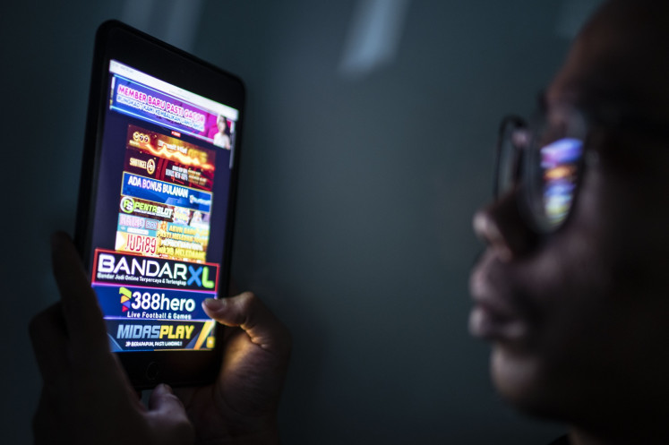 A user looks on advertisements for online gambling websites through his smartphone in Jakarta on June 19, 2024.