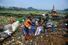 Workers use wooden boats to clear waste from a section of the Citarum River in Batujajar, West Bandung regency, West Java, on June 12, 2024. Authorities estimate that the floating garbage in the Citarum, often dubbed as the world's most polluted river, spans around 3 kilometers and weighs around 100 tonnes.