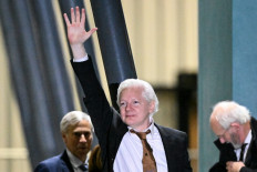 WikiLeaks founder Julian Assange (center) waves after arriving at Canberra Airport in Canberra on June 26, 2024, after he pleaded guilty at a US court in Saipan to a single count of conspiracy to obtain and disseminate US national defence information. 