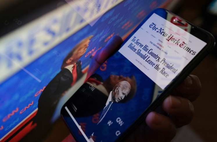 This illustration photo created on June 28, 2024 in Los Angeles, US, shows the New York Times editorial calling for President Joe Biden to leave the presidential race on a smartphone screen next to a screen showing a photo of former President Donald Trump during the June 27 presidential debate. America's most influential newspaper, The New York Times, called in an editorial on June 28 for President Joe Biden to step aside and allow another Democrat to challenge Donald Trump for the White House in November.  