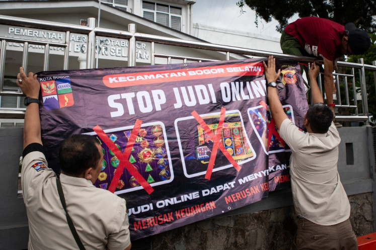 Local officials hang a public service announcement banner discouraging people from taking part in online gambling on June 30, 2024, outside a government building in Bogor, West Java.