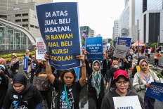 Protesters carry posters reading “Rigged government posts on top, rigged school admissions on the bottom“ (Di Atas Jual Beli Jabatan, Di Bawah Jual Beli Kursi Sekolah) on July 7, 2024, to protest against corruption and illegal levies on school enrollment during a Car Free Day (CFD) in Jakarta.