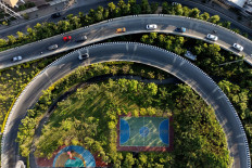 People play a match at a mini soccer field in a pocket park as vehicles pass the adjacent busy thoroughfare during the evening rush hour on April 26, 2024 in Bangkok.