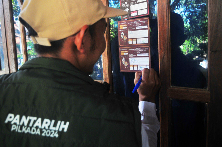 A voter data update worker (Pantarlih) signs a sticker on June 29, 2024, to verify the number and names of eligible voters at a residence in Kudus, Central Java, as part of preparations for the simultaneous regional head elections in November.