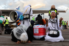 A haj pilgrim (right) lifts his head to the sky to pray while another performs sujud syukur (kneeling with one's face to the ground“ on June 23, 2024, after their plane landed safely at the Sultan Hasanuddin International Airport in Makassar, South Sulawesi.