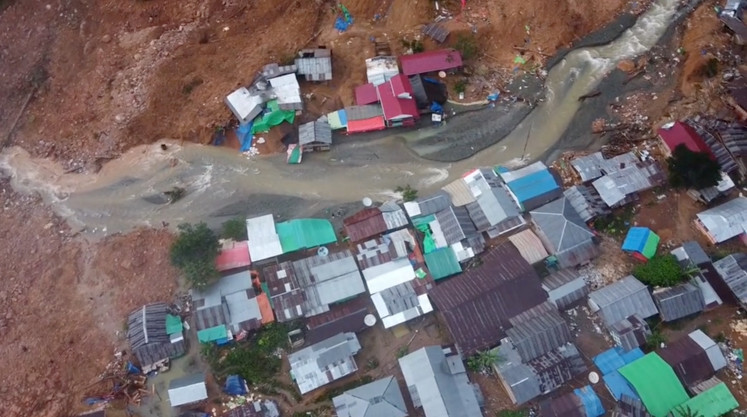Water flows amid buildings buried under mud and debris in the aftermath of a landslide on July 8, 2024, following torrential rain in the district of Suwawa in Gorontalo, in this still image obtained from a social media video.