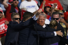 Secret Service agents surround Republican presidential candidate former President Donald Trump onstage after he was injured at a rally on July 13, 2024 in Butler, Pennsylvania. According to Butler County District Attorney Richard Goldinger, the suspected gunman is dead after injuring former President Trump, killing one audience member and injuring at least one other.  