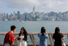 Mainland Chinese tourists take photo of the skyline of buildings at Tsim Sha Tsui, in Hong Kong, China, on May 2, 2023.