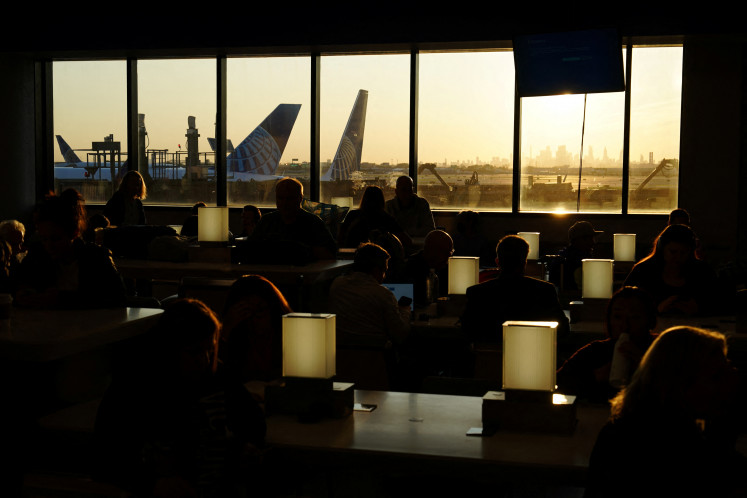 Travelers wait for delayed flights beneath a monitor displaying a blue error screen, also known as the ?Blue Screen of Death? inside Terminal C in Newark International Airport, after United Airlines and other airlines grounded flights due to a worldwide tech outage caused by an update to Crowdstrike's “Falcon Sensor“ software which crashed Microsoft Windows systems, in Newark, New Jersey, U.S., July 19, 2024. 