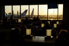 Travelers wait for delayed flights beneath a monitor displaying a blue error screen, also known as the ?Blue Screen of Death? inside Terminal C in Newark International Airport, after United Airlines and other airlines grounded flights due to a worldwide tech outage caused by an update to Crowdstrike's “Falcon Sensor“ software which crashed Microsoft Windows systems, in Newark, New Jersey, U.S., July 19, 2024. 