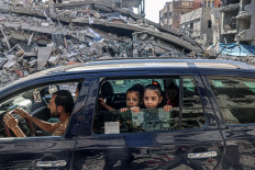 Palestinians drive amid the rubble of buildings destroyed in an Israeli air strike in Rafah, in the southern Gaza Strip on October 12, 2023.