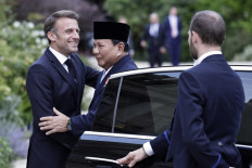 French President Emmanuel Macron (left) welcomes Defense Minister and president-elect Prabowo Subianto (center) on July 24, 2024, upon arriving for a working dinner at the Elysee presidential Palace in Paris.