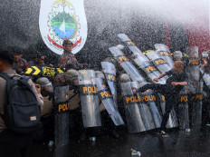 A protester kicks police personnel taking cover behind riot shields during a protest in Mamuju, West Sumatra on July 10, 2024 organized by the Association of Islamic Students (HMI) chapter in the city.