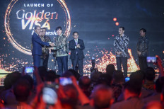 President Joko “Jokowi“ Widodo (left) symbolically hands over a golden visa to Indonesian soccer national team coach Shin Tae-yong (fourth left) during the golden visa launching event in Jakarta on July 25, 2024.