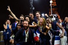 Members of France's delegation pose on the Iena Bridge during the opening ceremony of the Paris 2024 Olympic Games in Paris on July 26, 2024, as the Eiffel Tower is seen in the background.