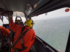 This handout photo taken on July 25, 2024 and received from the Philippine Coast Guard (PCG) shows Coast Guard personnel aboard a helicopter conducting an aerial survey off Manila, after oil tanker MT Terra Nova capsized. A Philippine-flagged tanker MT Terra Nova carrying 1.4 million liters of industrial fuel oil capsized and sank off Manila on July 25, authorities said, as they raced against time to contain the spill.