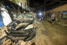 Men walk past debris and a destroyed car after the top floors of an eight-storey building were destroyed following an Israeli military strike in a Beirut's southern suburb, on July 30, 2024. The Israeli military said it carried out a strike on July 30, in Beirut that targeted a Hezbollah commander responsible for the killing of children in last week's rocket attack on the Golan Heights. A source close to Hezbollah told AFP that a senior commander was targeted in an Israeli strike on its south Beirut stronghold. 