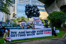Activists hold up a bunch of balloons bearing the names of hazardous and toxic emissions produced as a by-product of coal at a protest in Jakarta on May 15, 2024, during coal miner Adaro’s general meeting of shareholders.