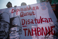 Protesters hold posters that read “Dipisahkan Qunut, Disatukan Tambang“ (Separated by Qunut, United by Mining) on July 27, 2024, during a protest against Islamic group Muhammadiyah's decision to accept the government's offer on coal mining concessions in Sleman, Yogyakarta.