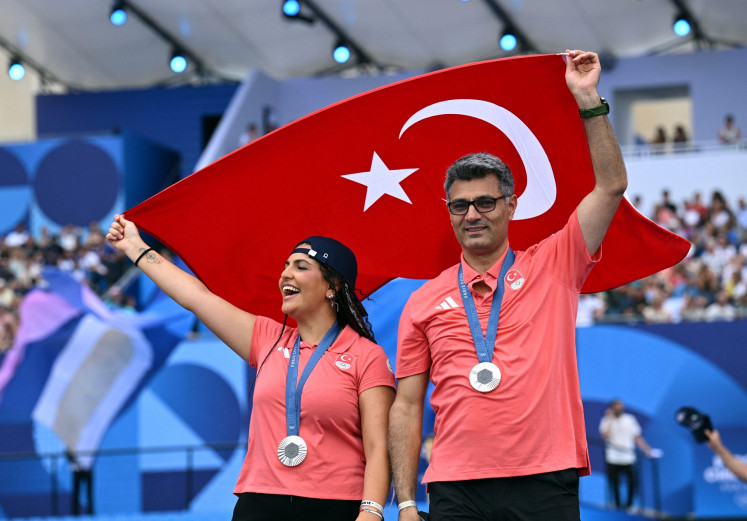 Shooting mixed silver medalist Sevval Ilayda Tarhan (left) and Yusuf Dikec of Turkey pose with their medals and the flag of Turkey during the Champions Park medalists celebrations in Paris on July 31, 2024.