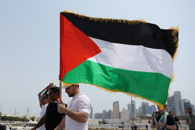 A man holding a Palestinian flag walks with others towards the Imam Muhammad bin Abdul Wahhab Mosque in Doha to bid farewell Hamas leader Ismail Haniyeh after his killing in Tehran in an attack blamed on Israel, on Aug. 2, 2024. Haniyeh, who resided in Doha along with other members of the Hamas political office, will be buried at a cemetery in Lusail, north of the Qatari capital after funeral prayers at Imam Muhammad bin Abdul Wahhab mosque, the Gulf emirate's largest.
