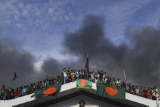 Anti-government protestors display Bangladesh's national flag as they storm Prime Minister Sheikh Hasina's palace in Dhaka on August 5, 2024. Bangladesh army chief Waker-Uz-Zaman spent nearly four decades rising to the top of the military and said on August 5, he was “taking full responsibility“ after Prime Minister Sheikh Hasina was ousted and fled. 