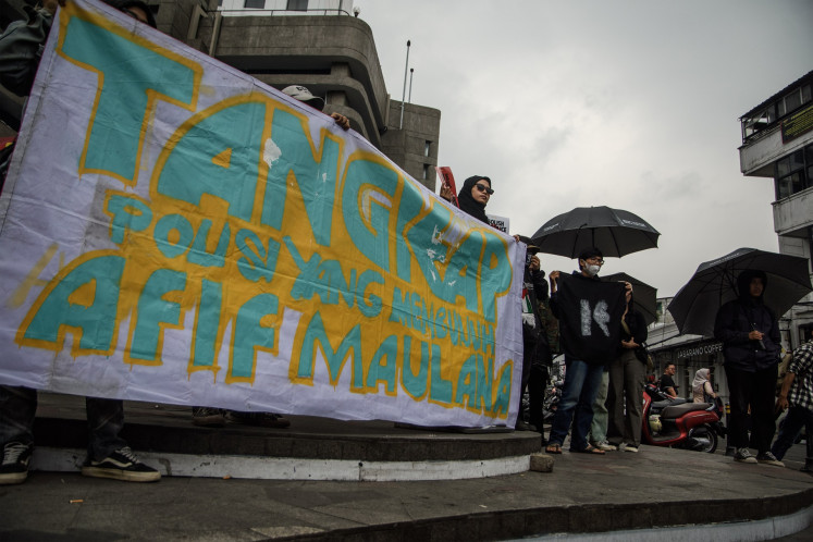 Protesters hold banners during a protest in Bandung, West Java, on July 18, 2024 urging the police to investigate thoroughly the death of AM, a 13-year-old boy in Padang, West Sumatra, who was allegedly beaten to death by police officers after being suspected of inciting brawl.