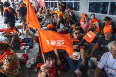 Supporters of the Move Forward Party (MFP), decked out in the party’s iconic orange paraphernalia and waving flags, gather on Aug. 7, 2024 at its Bangkok headquarters to await the Constitutional Court’s ruling on the future of the MFP and its former leader Pita Limjaroenrat.
