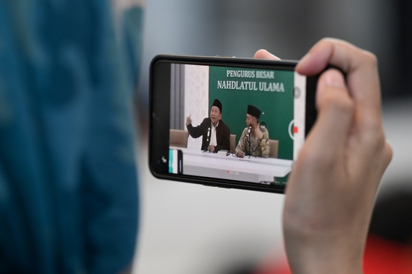 A journalist records a video of a press briefing with former National Awakening Party (PKB) politician Effendy “Gus Choi“ Choirie (left) and a Nahdlatul Ulama executive Ishaq Zubaedi Raqib (right) at the NU office in Jakarta on Aug. 7, 2024.