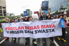 Protesters hold a banner that reads “No fees for state and private schools“ during a protest demanding free education at a car-free day event in Jakarta on July 7, 2024.