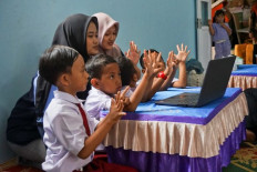 Internet schooling: Elementary school pupils in Banteng village, Batang regency, Central Java, accompanied by their teachers, watch on Aug. 8, 2024 YouTube live streaming of education materials during the launch of an internet for villages program initiated by the local government.