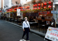 A man walks past a restaurant with a water sprayer on its roof during a hot summer day in Shimbashi, Tokyo, on Aug. 13, 2024.