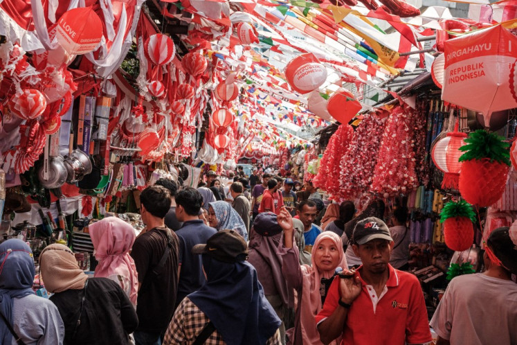 People buy decorations in the national flag colours of red and white on a street in Jakarta on August 11, 2024, ahead of Indonesia's 79th Independence Day on August 17. 