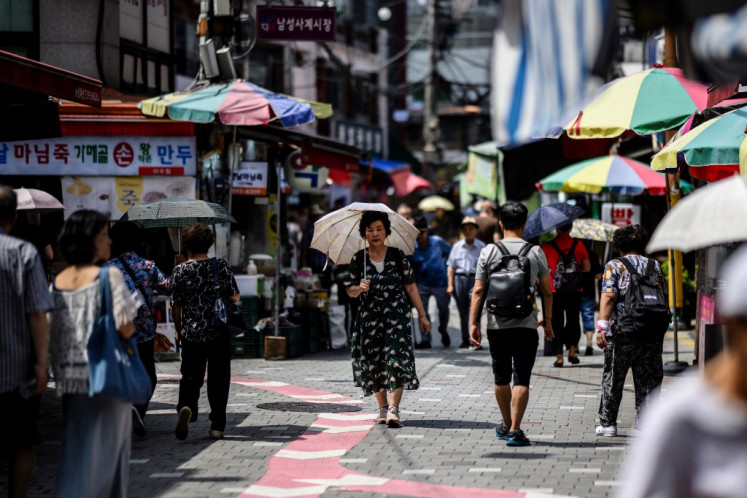 A women uses an umbrella to shield from the sun at a market in Seoul on August 16, 2024, during a prolonged heatwave which has gripped much of the country. 