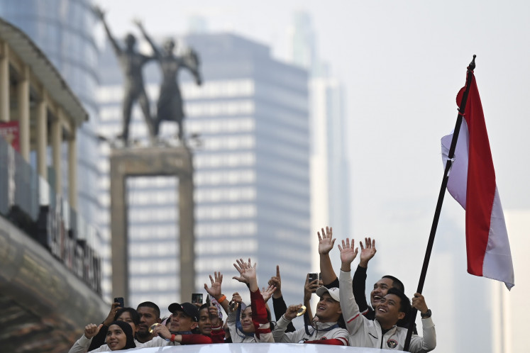 On a thoroughfare near Jakarta's Hotel Indonesia (HI) traffic circle, athletes and officials ride a roofless double-decker bus in a procession from the Youth and Sports Ministry to the State Palace on Aug. 15, 2024. The march was organized to welcome home the Indonesian athletes who competed in the 2024 Olympic Games in Paris, including winners Rizki Juniansyah (weightlifting), Veddriq Leonardo (speed climbing) and Gregoria Mariska Tunjung (badminton).