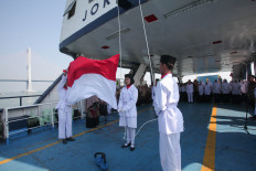 Students of SMP Muhammadiyah 2 Surabaya junior high school raise the Red and White national flag on Aug. 17, 2024, during an Independence Day ceremony aboard a ferry anchored in the Madura Strait, off the coast of East Java.