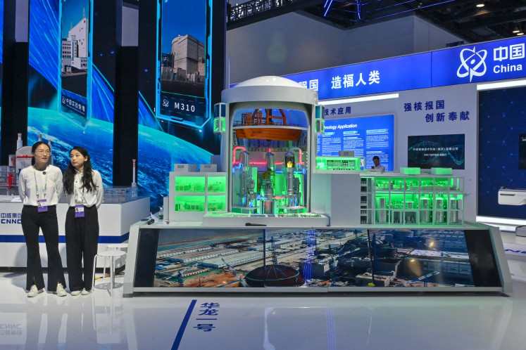 Attendants await visitors on July 16, 2024, next to a thermal nuclear reactor model during the 26th China Beijing International High-Tech Exhibition at the National Convention Center in Beijing.